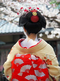 Rear view of woman wearing kimono against cherry tree