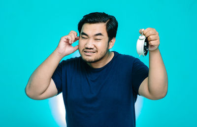 Young man standing against blue background
