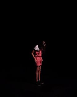 Woman standing against black background