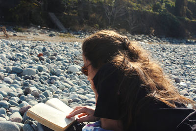 Young woman reading book on the beach, sun and summer holidays in black sea