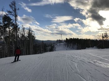 Rear view of person on snow covered landscape against sky