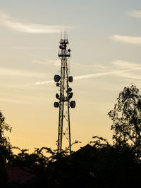 Low angle view of communications tower against sky during sunset