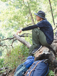 Side view of man sitting on tree trunk
