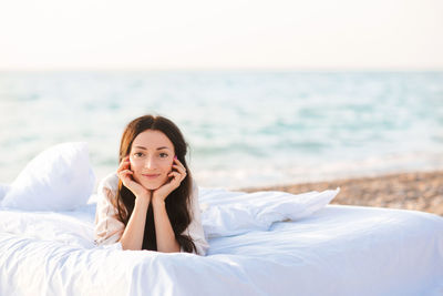 Portrait of beautiful young woman sitting on beach