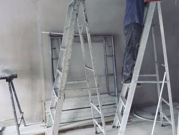Low section of worker standing on step ladder at construction site