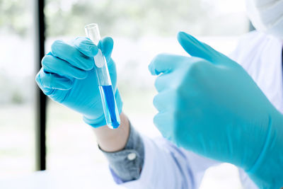 Midsection of scientist holding test tube at laboratory