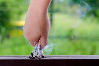 Close-up of human hand stubbing cigarettes on table