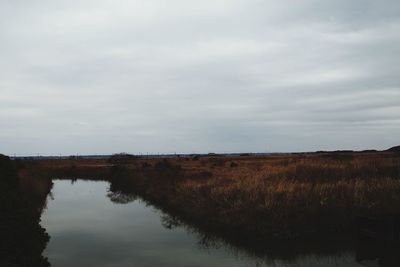 Scenic view of field and lake against sky