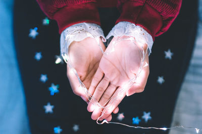 Cropped hands of woman holding illuminated string lights