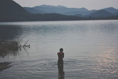 Rear view of woman standing in lake