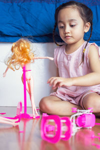 Cute girl playing with doll at home