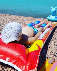 High angle view of shirtless boy lying on pool raft at beach