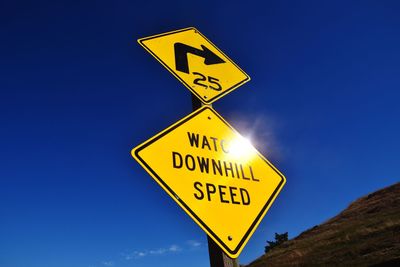 Low angle view of road sign against blue sky