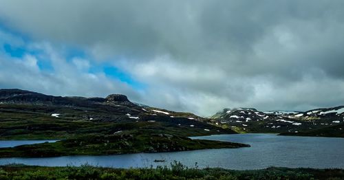 Scenic view of lake by mountains against sky