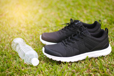 Close-up of shoes and water bottle on grass