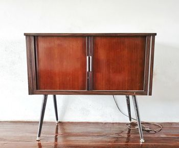 Wooden table and chairs on hardwood floor against wall