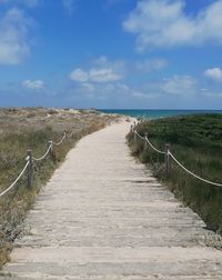 Footpath leading towards sea against sky