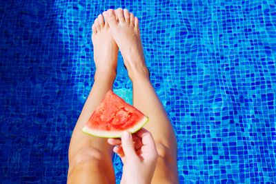 Low section of woman feet against blue swimming pool