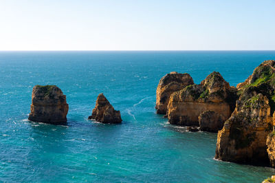 Scenic view of rocks in sea against clear sky