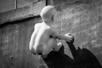 Rear view of shirtless boy on wall