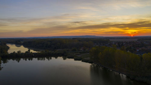 Scenic view of river by buildings against sky during sunset