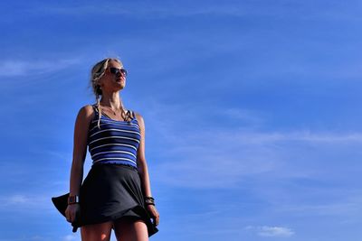 Low angle view of woman standing against blue sky