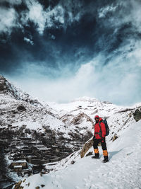 Rear view of man on snow covered mountain against sky