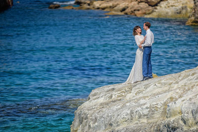 Couple standing on rock by sea