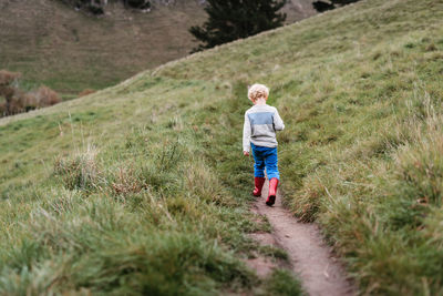 Little curly haired boy walking on a hillside path