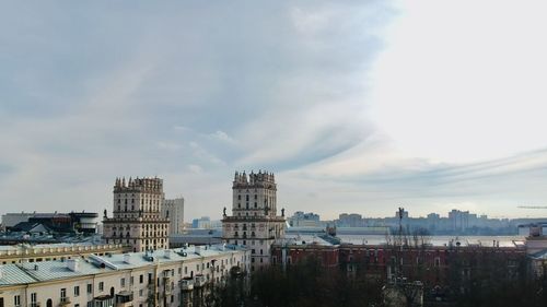 Buildings by river against sky in city