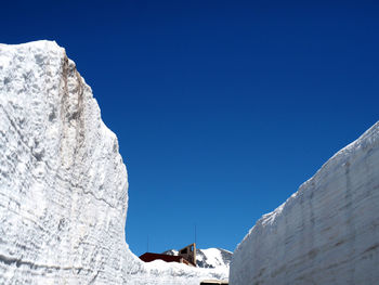 Low angle view of snow against clear blue sky