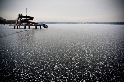 Slide in frozen lake against clear sky