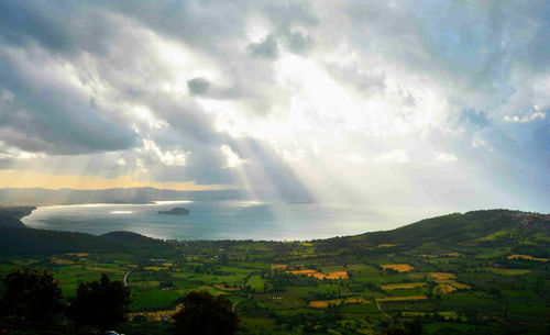 Sunlight streaming through clouds over landscape