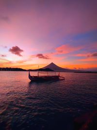 Silhouette sailboat in sea against sky during sunset