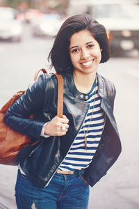 Portrait of smiling young woman standing in city