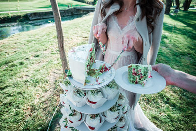 Low section of woman serving slice of cake at park