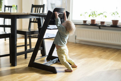 Toddler with down syndrome hanging on high chair