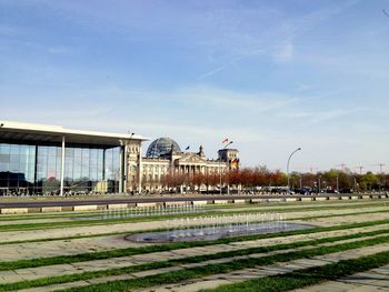 Fountain by bundestag against sky in city