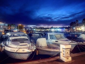 Boats moored in illuminated city at night