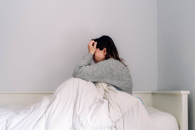 Woman sitting on bed at home