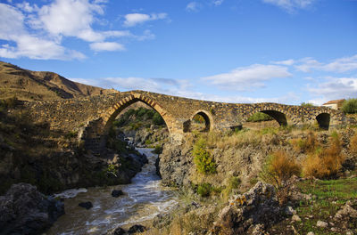 Stone bridge over river against sky