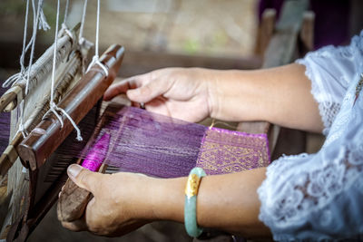 Cropped hands of woman working on loom in workshop