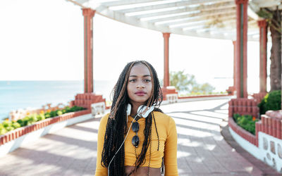 Portrait of beautiful young woman standing against sky