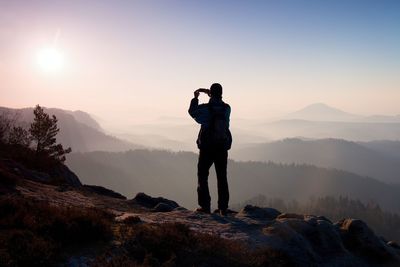 Rear view of man photographing at sunset