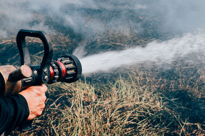 Cropped hand spraying water in burning forest
