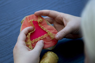 Woman wrapping a red foam heart in gold fabric