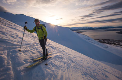 Man skiing in iceland at sunrise with water behind him
