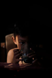 Close-up portrait of young man holding camera in darkroom