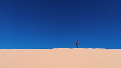 Man on sand dune against clear sky