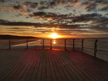 Pier over sea against sky during sunset